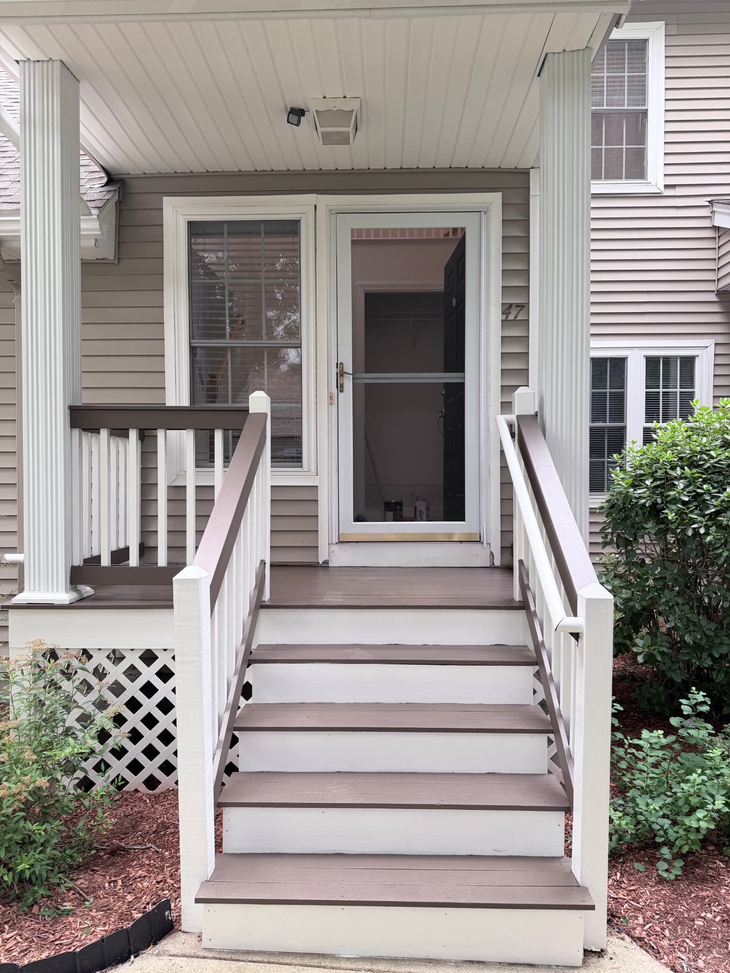 Exterior entry porch with freshly finished trim, columns and railings