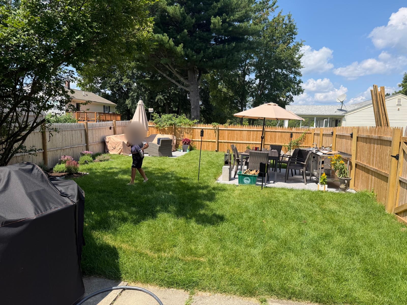 Completed Shrewsbury backyard with a healthy lawn, landscaped borders and outdoor dining area