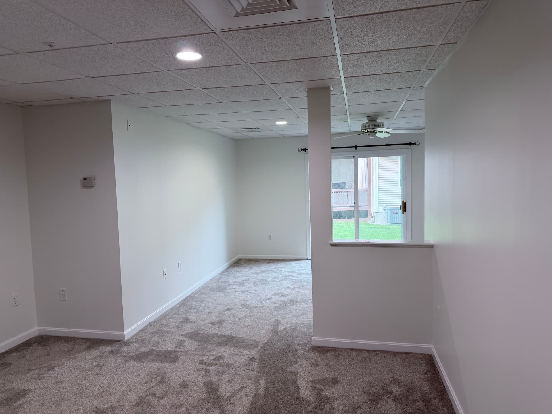 Repainted lower-level living space with soft white walls and new carpet